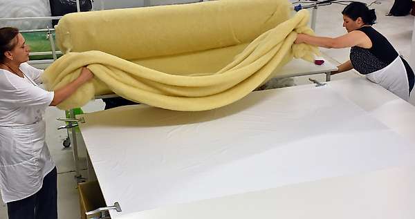 Mise en place de la première couche de nappe de laine aérée sur le tissu.