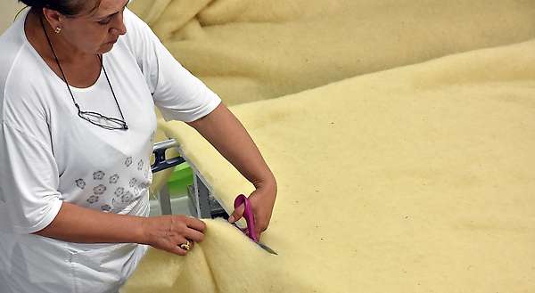 Découpe de la laine en excès. Cette laine est réutilisée dans d’autres produits comme les coussins ou retournée chez le fournisseur des nappes pour être réutilisée.