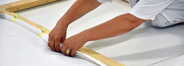 The quilt is stitched on each needle of the frame to maintain it. This requires some experience not to prick oneself.