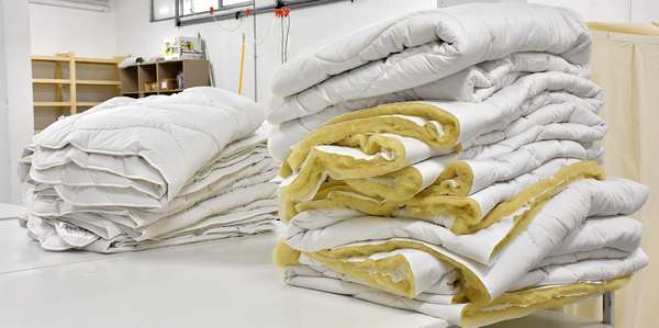 2 piles of duvets, one of quilts ready to be packed, the other of quilts waiting for finishing.