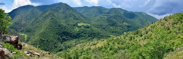 Panorama na kanjonu Uvac. Neasfaltirani put koji silazi prema manastiru Uvac se vidi na desnoj strani slike, a manastir se može videti u centru druge slike.